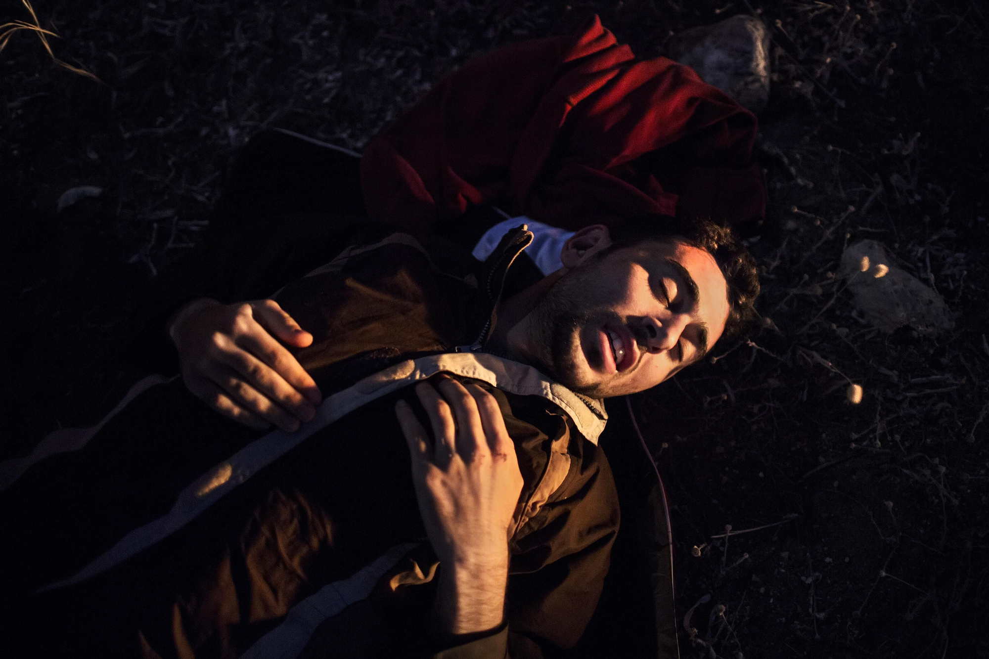 Un joven sirio trata de recuperarse del viaje en una playa de Kos tras alcanzar la costa en una barcaza junto a otras 40 personas. Las condiciones de hacinamiento y el oleaje han provocado que, durante la travesía, uno de sus compañeros le haya caído encima de sus rodillas. Es incapaz de mover las piernas. | Fotografía: Alessandro Penso/MSF.