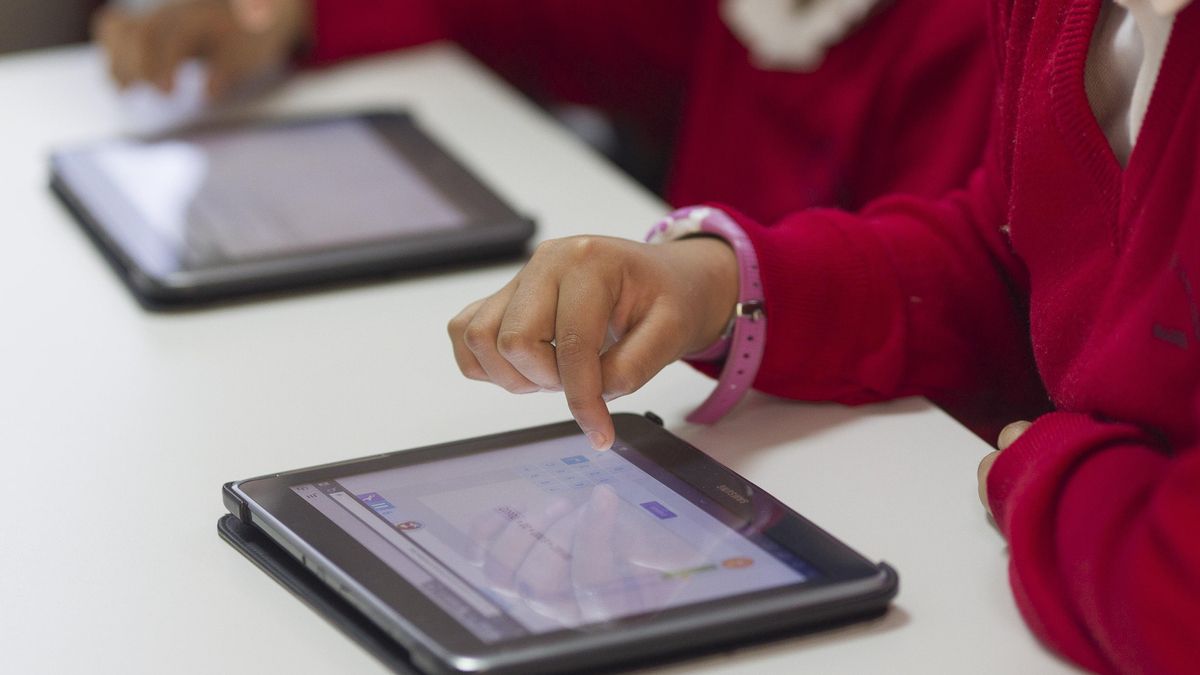 Alumnos en un aula con dispositivos digitales