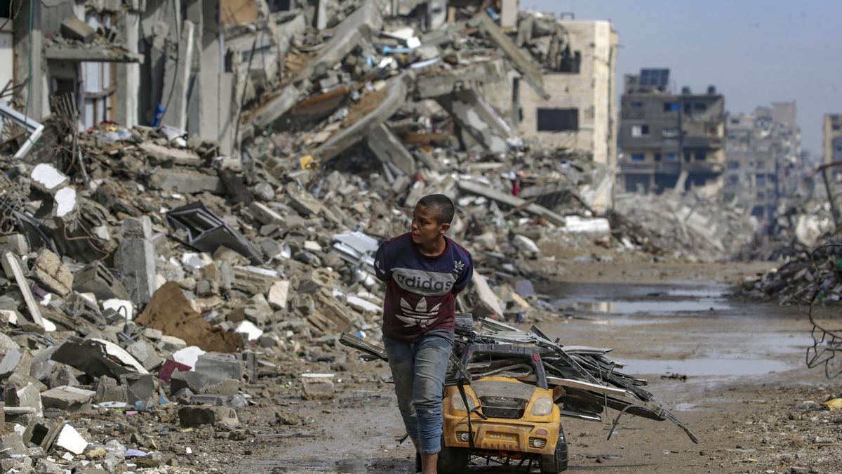 Nesta sexta-feira, uma criança coleta sucata usando um carrinho de brinquedo no bairro de Radwan, no norte da cidade de Gaza.