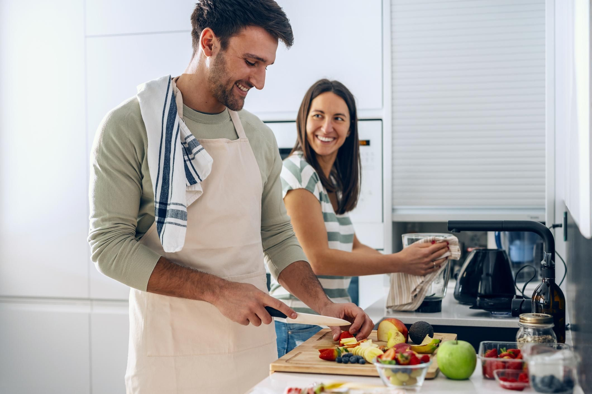 Una pareja corta fruta en la cocina