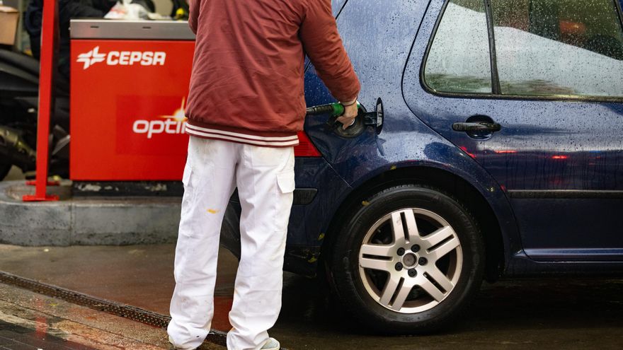 Una persona echa gasolina del surtidor de una gasolinera.