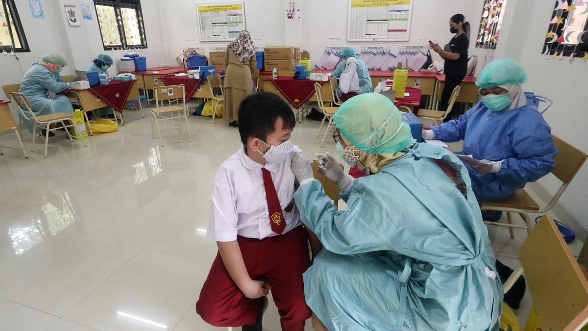 An Indonesian health worker gives a dose of COVID-19 vaccine to an elementary school student during a vaccination drive for children between the ages of six to 11, at an SDN 01 elementary school in Depok, West Java, Indonesia, 14 December 2021.