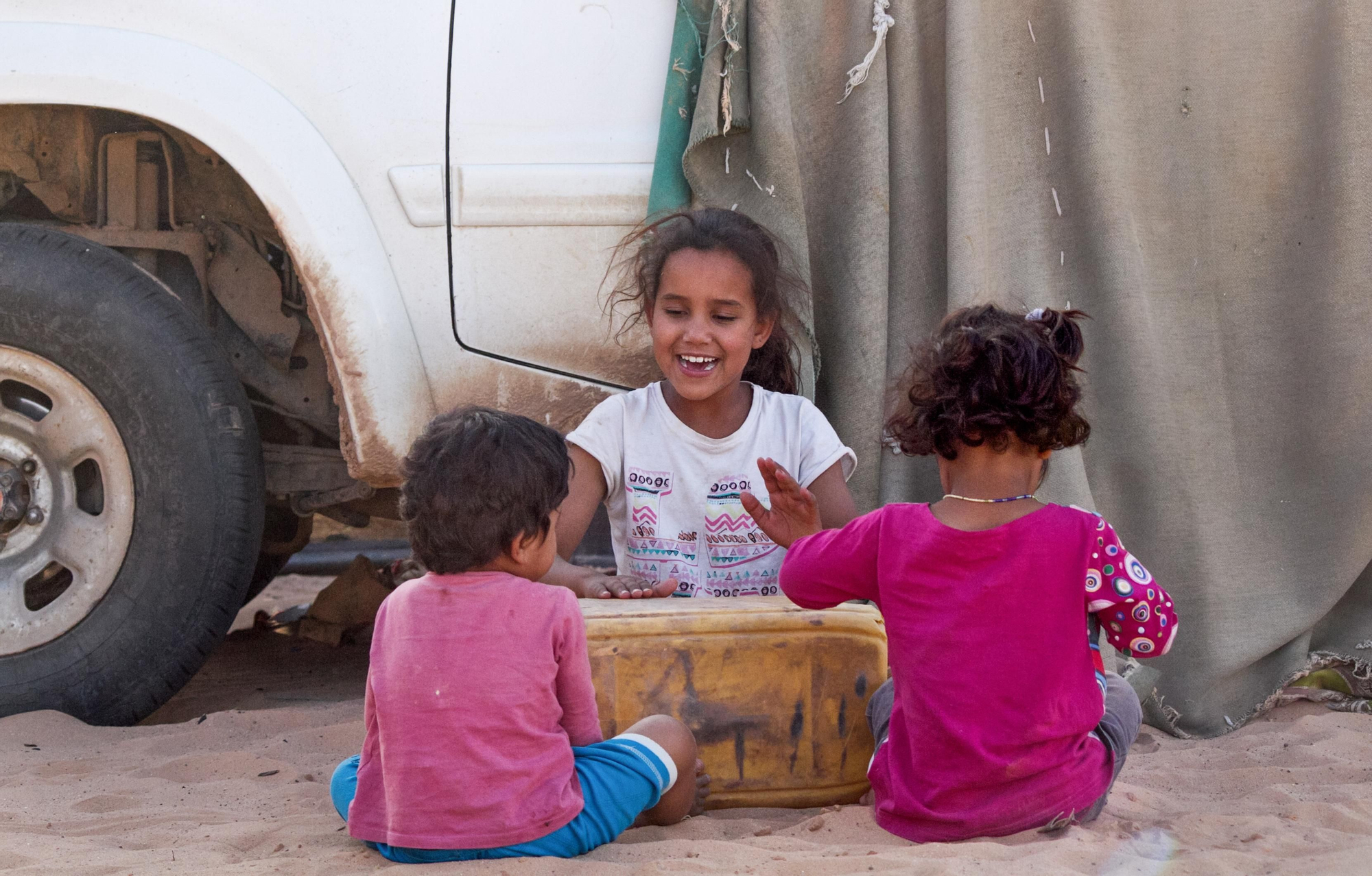 Niños saharauis juegan junto a un vehículo.