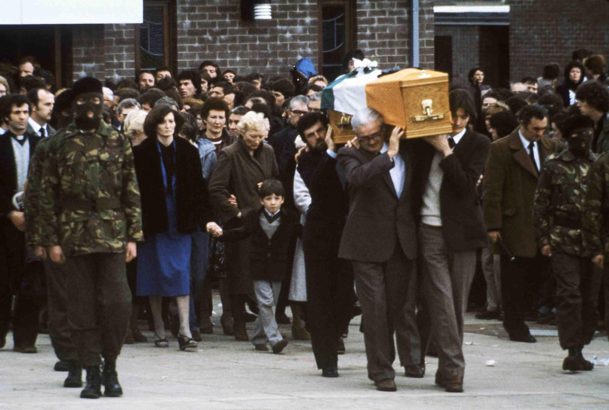 Gerard Sands, 7, follows behind the coffin of his father, IRA hunger striker Bobby Sands, as it leaves a church near his home, en route to Belfast’s Milltown cemetery on Thursday, May 7, 1981 escorted by masked IRA men. Carrying the coffin, from right, are Sands’ brother, his father and his political agent Owen Carrow, while his sister Marcela holds his son’s hand. (AP Photo/Robert Dear)