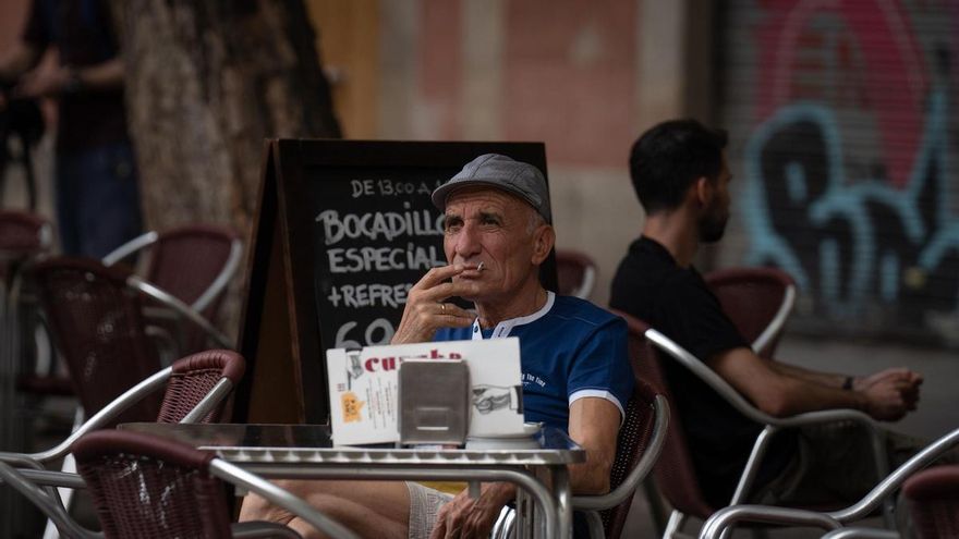 Un hombre fuma un cigarrillo en la terraza de un bar de Barcelona.