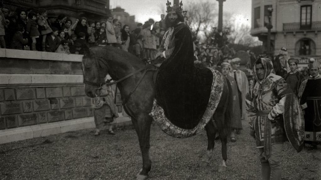 Los Reyes Magos delante del Ayuntamiento de Donostia, antiguo Casino, desfilando por el puente de la Zurriola y entregando regalos a los niños en 1930