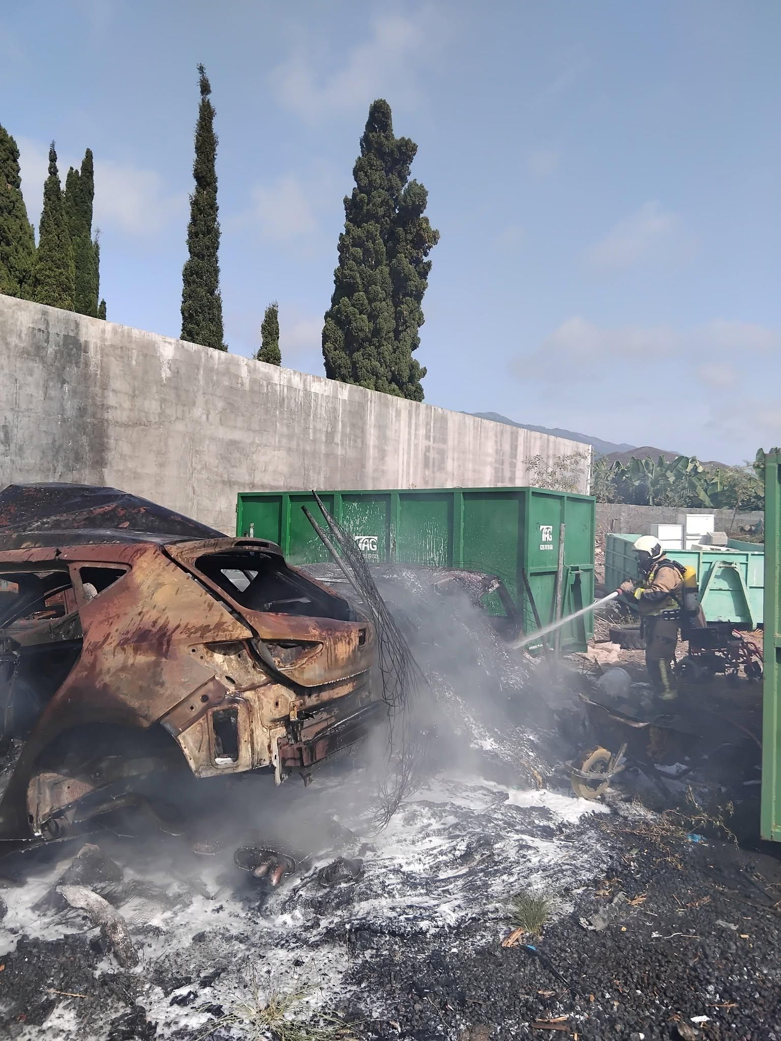 Un bombero apagando el incendio de dos vehículos y otros materiales en un depósito provisional del Ayuntamiento de Tazacorte.
