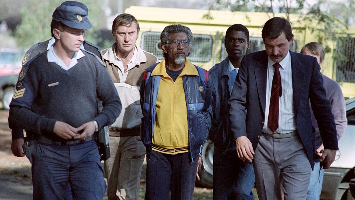 Mac Maharaj escoltado por la policía para asistir al funeral de su hermana en 1990.