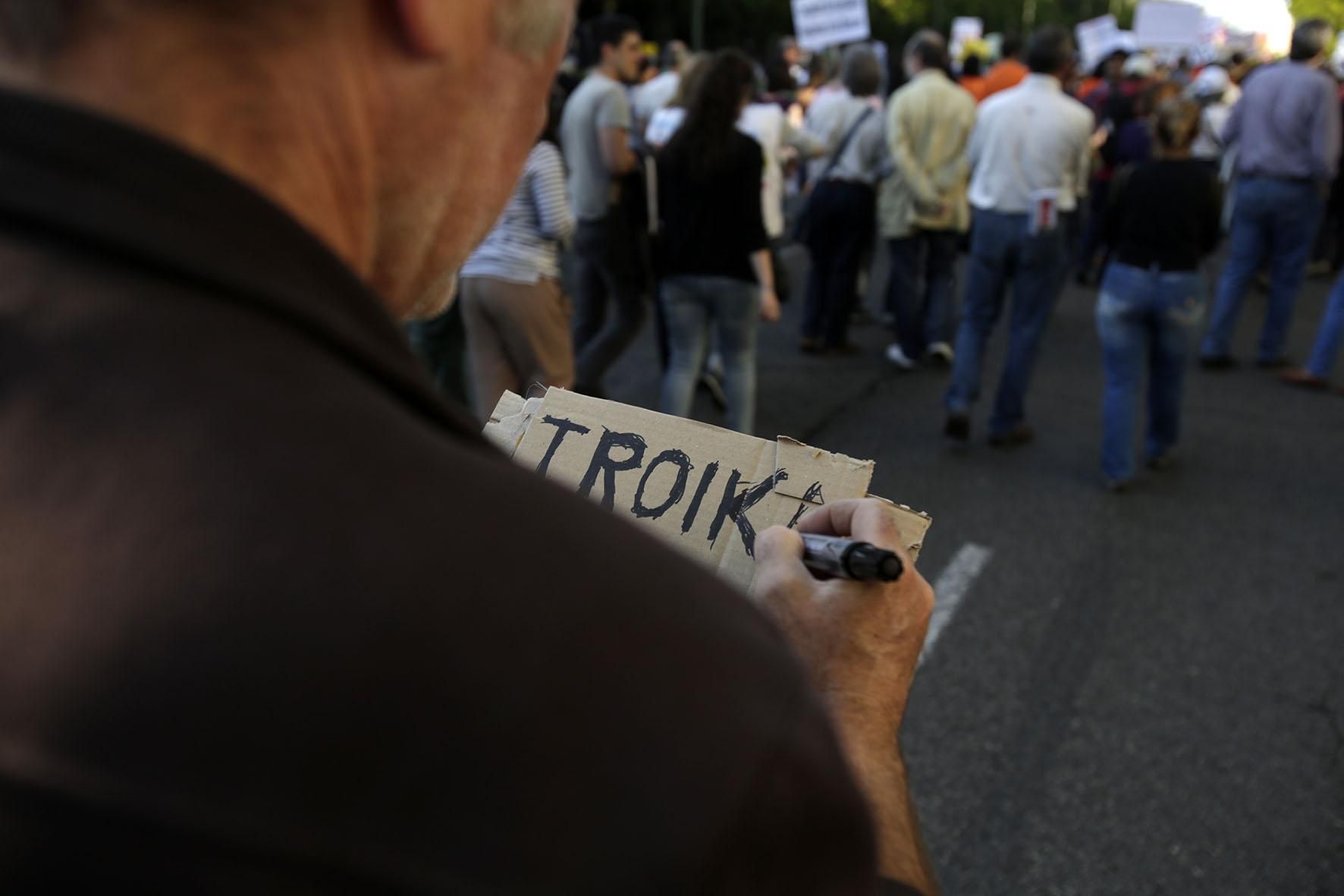 Un manifestante prepara su cartel contra la troika