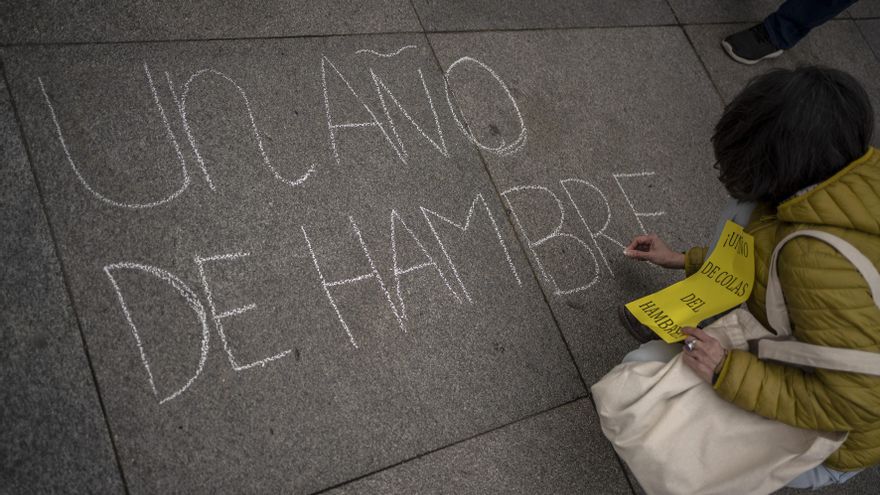 "Un año del hambre", escribe en el suelo una manifestante de la protesta frente al Ayuntamiento de Madrid para denunciar un año de inacción política