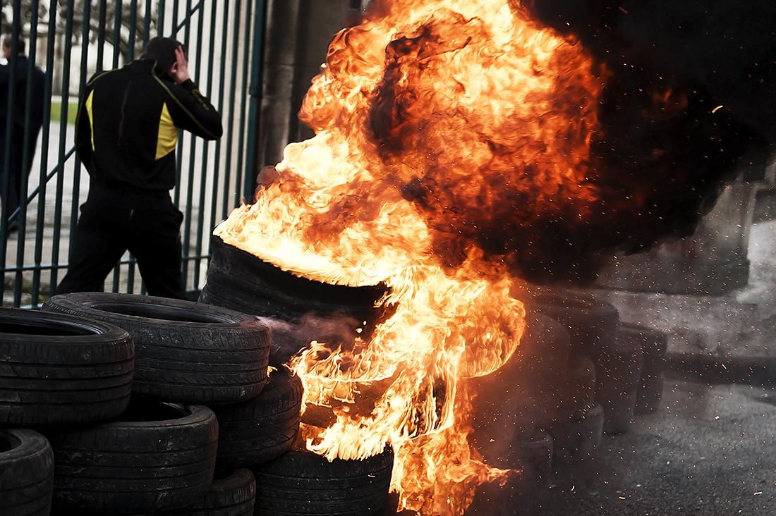 Un trabajador de SNIACE pasa por delante de unos neumáticos ardiendo en frente de las puertas de la factoría de Torrelavega, en uno de los cortes que han realizado a las entradas de la fábrica, durante las protestas por su situación laboral. | PEDRO PUENTE HOYOS (24/01/2014)