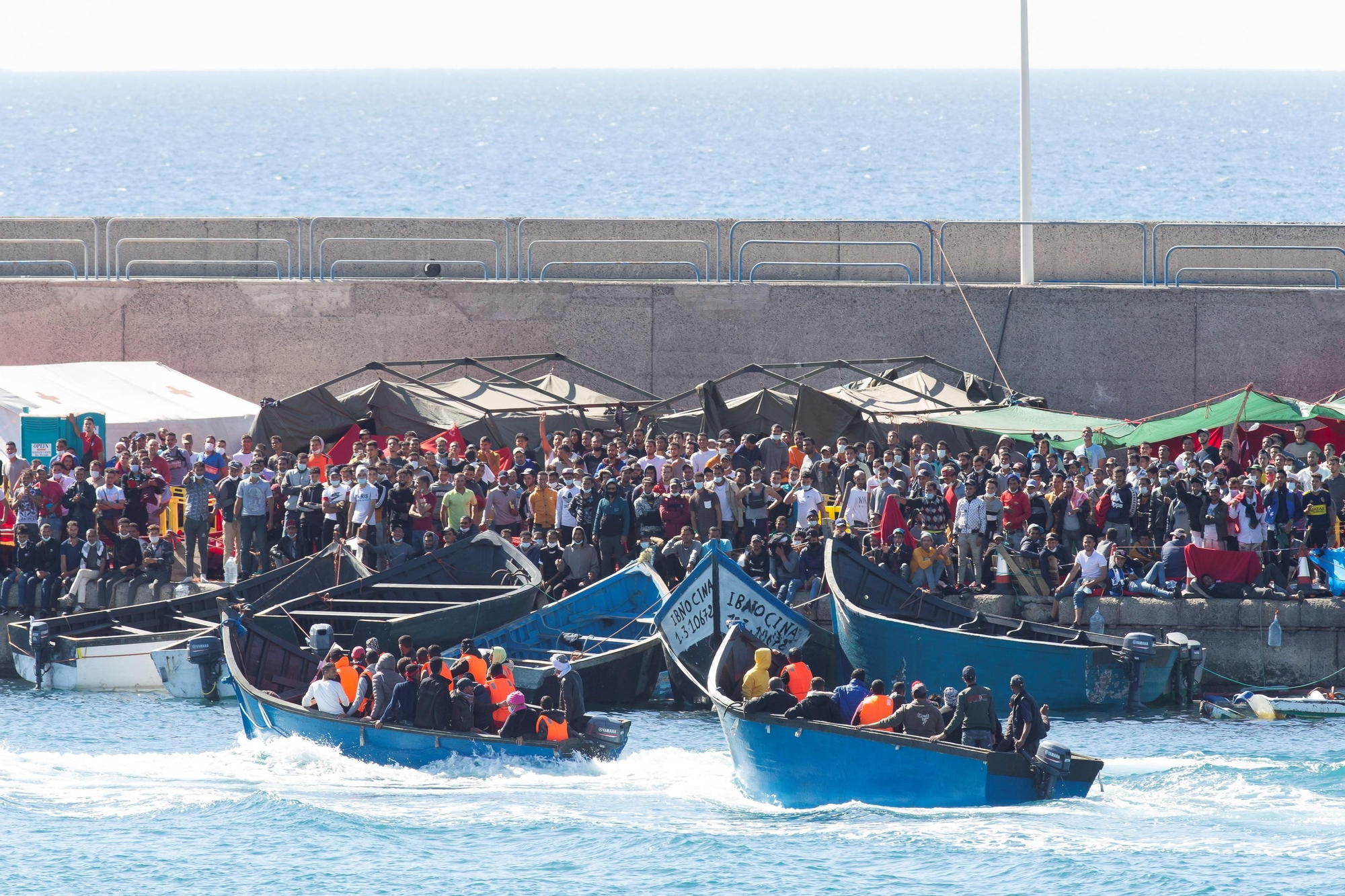 Imagen de archivo de cayucos llegando al muelle de Arguineguín, con el campamento de Cruz Roja al fondo, en noviembre de 2020. 