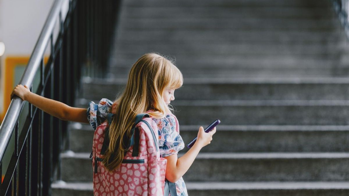 Una niña usando el móvil en el colegio