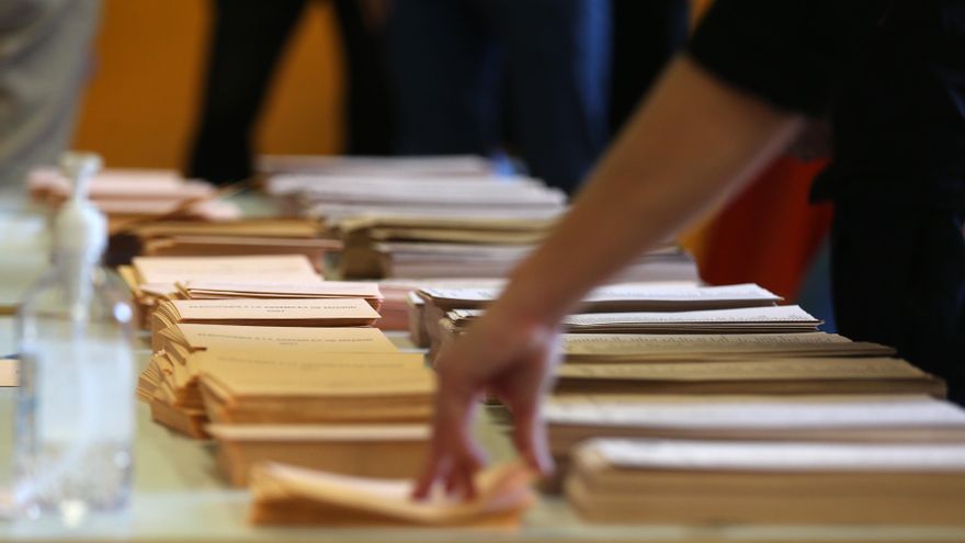 Archivo - Una persona coge un sobre para votar