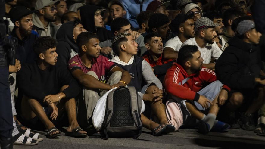 Migrantes esperan para poder entrar al campamento del puerto de Ceuta.