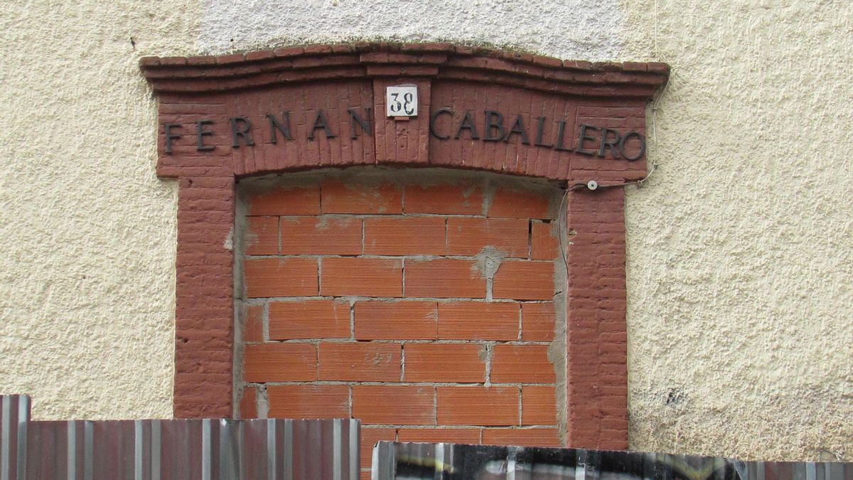 Puerta principal de antiguo colegio Fernán Caballero, tapiada con  ladrillo rojo y vallada por una barrera de aluminio