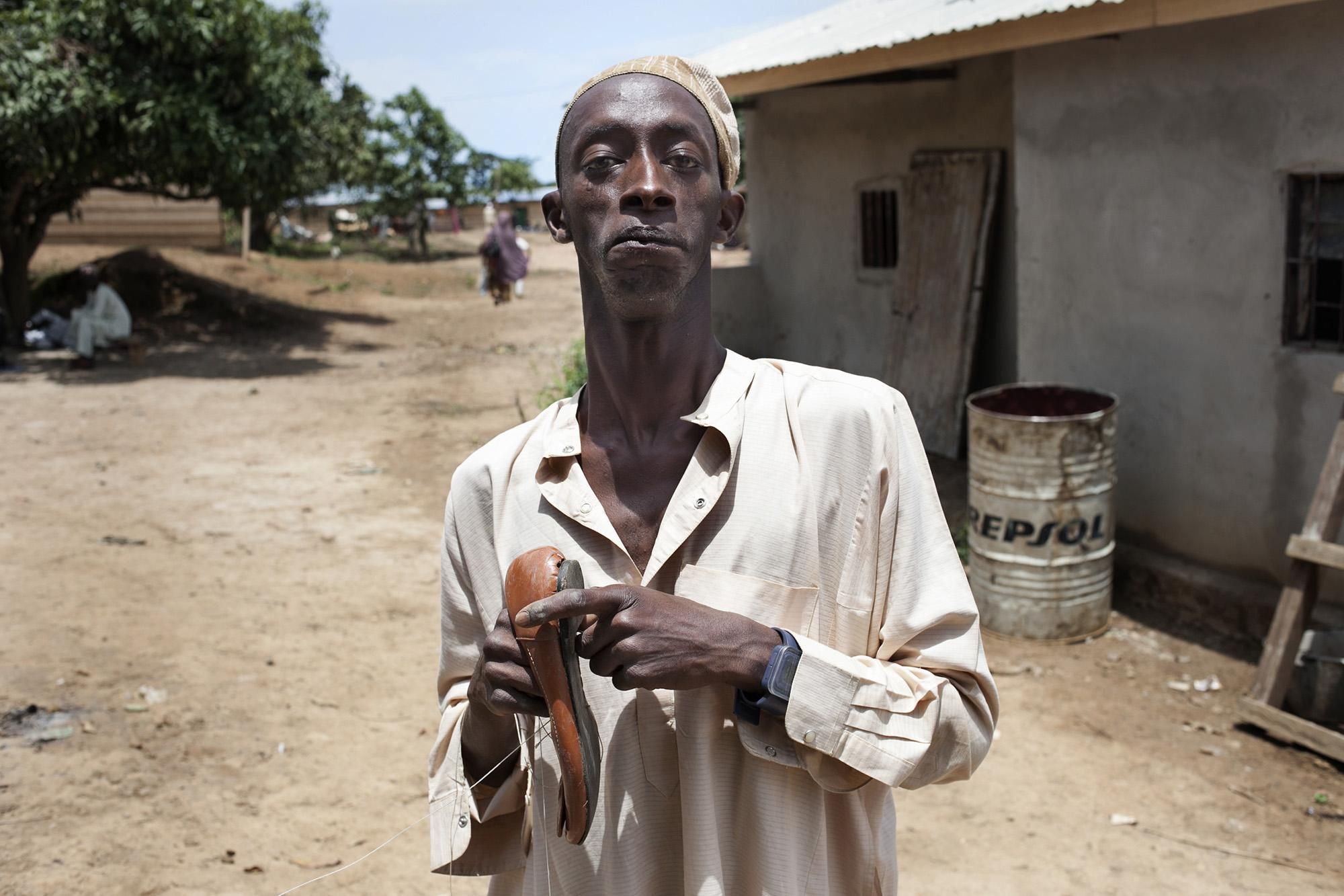 Ahbra Hamajora tiene 30 años y vive en el campo de Adf. Cuenta que es de los pocos supervivientes de su pueblo natal después de varios ataques de las milicias Anti-Balaka en diciembre de 2013. Ahbra es Zapatero y es el único refugiado del campo que ha continuado con su actividad anterior./ Albert Masias