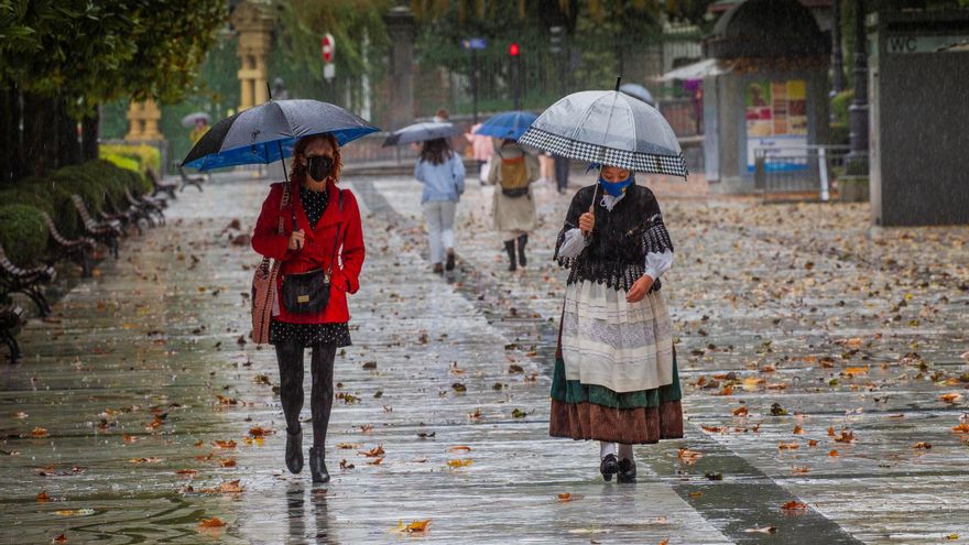 Dos mujeres pasean bajo la lluvia en el paseo de Los Álamos, en el centro de Oviedo, Asturias.  EFE/Alberto Morante