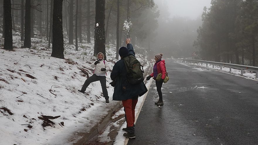 Varios curiosos que se acercaron a la cumbre juegan con la nieve