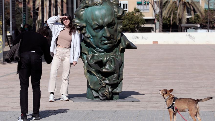 Varias personas junto a una de las figuras instaladas por la ciudad de Valencia del busto de Goya realizado por el escultor Mariano Benlliure a principios del Siglo XX y que recuerdan a los valencianos la celebración de la gala de los Premios Goya en el Palau de Les Arts el próximo sábado 12 de Febrero
