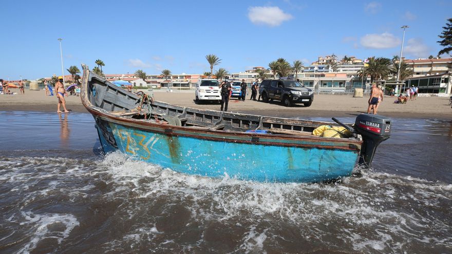 Agentes de la Policía y trabajadores de la Cruz Roja esperando a la retirada de una patera llegada a la turística Playa de Las Burras.