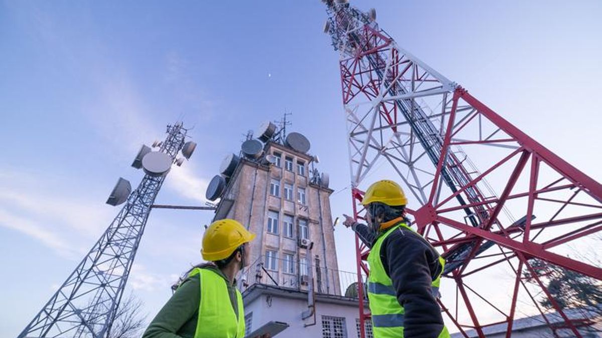 Ingenieros trabajan junto a una torre de telecomunicaciones.