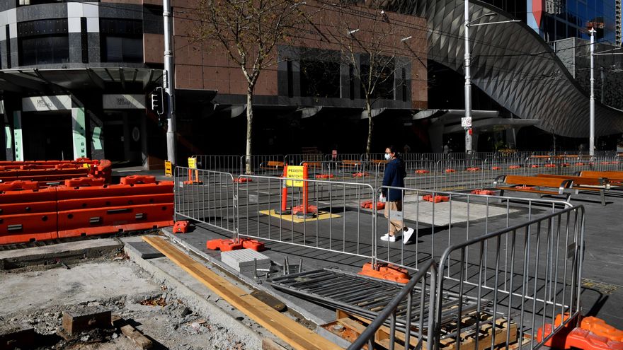 Los peatones con mascarillas pasan por una obra en construcción en el distrito central de negocios en Sídney, Australia, 28 de julio de 2021. EFE/EPA/ JOEL CARRETT