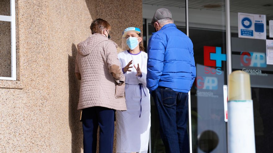 Una sanitaria atiende a dos personas a la entrada del Centro de Salud de Cazoña.