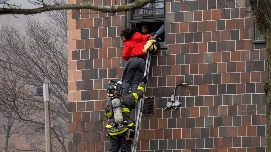 Un bombero eleva una escalera para rescatar a personas a través de sus ventanas en el incendio provocado en un edificio en El Bronx, EEUU.