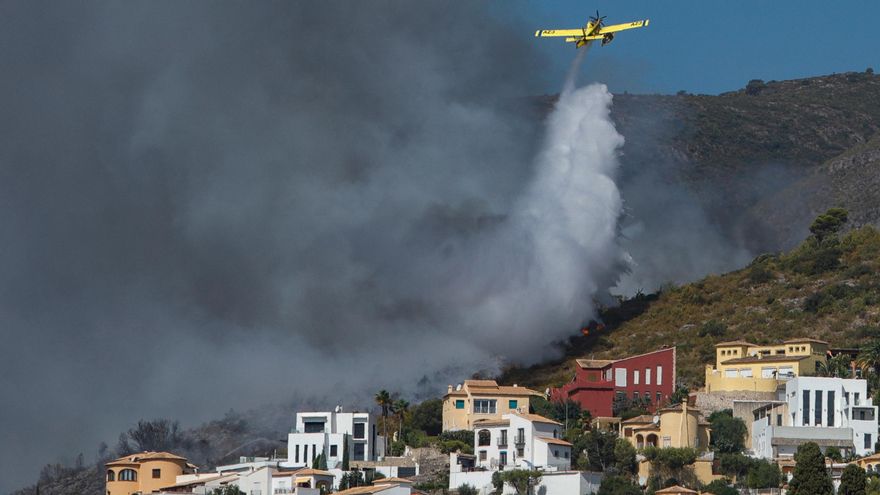 Una avioneta realiza una descarga de agua sobre las llamas que avanzan hacia una zona de viviendas en la Atzubia (Alicante).