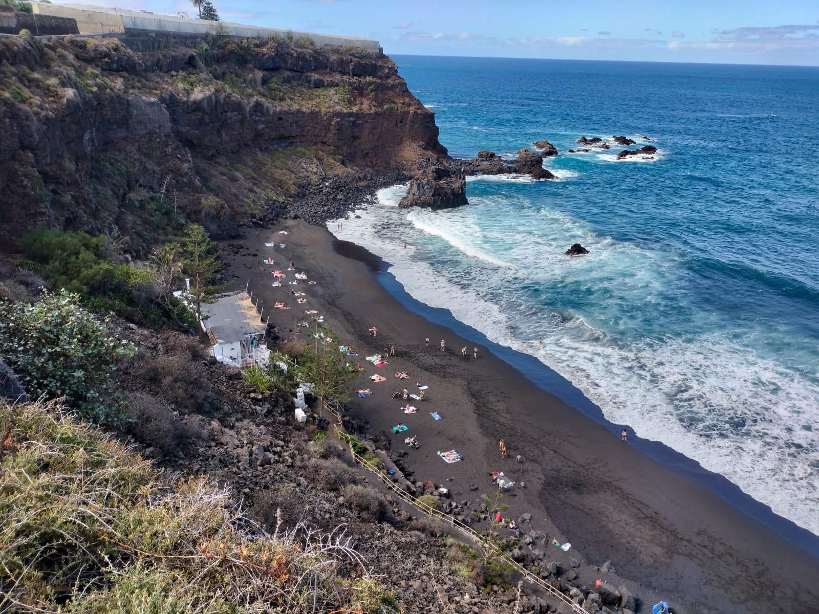 Playa de El Bollullo, con el chiringuito junto a la arena, si bien el restaurante y los aparcamientos se sitúan encima del acantilado.