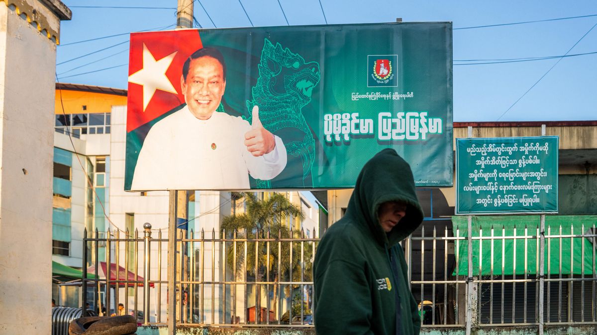 Un hombre pasa junto a un cartel electoral del promilitar Partido Unión Solidaridad y Desarrollo, en Lashio (Myanmar) el 20 de diciembre.