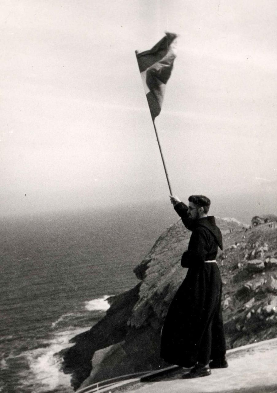 Un fraile ondea una bandera española en un acto de homenaje a los supuestos asesinados en Cabo Mayor.