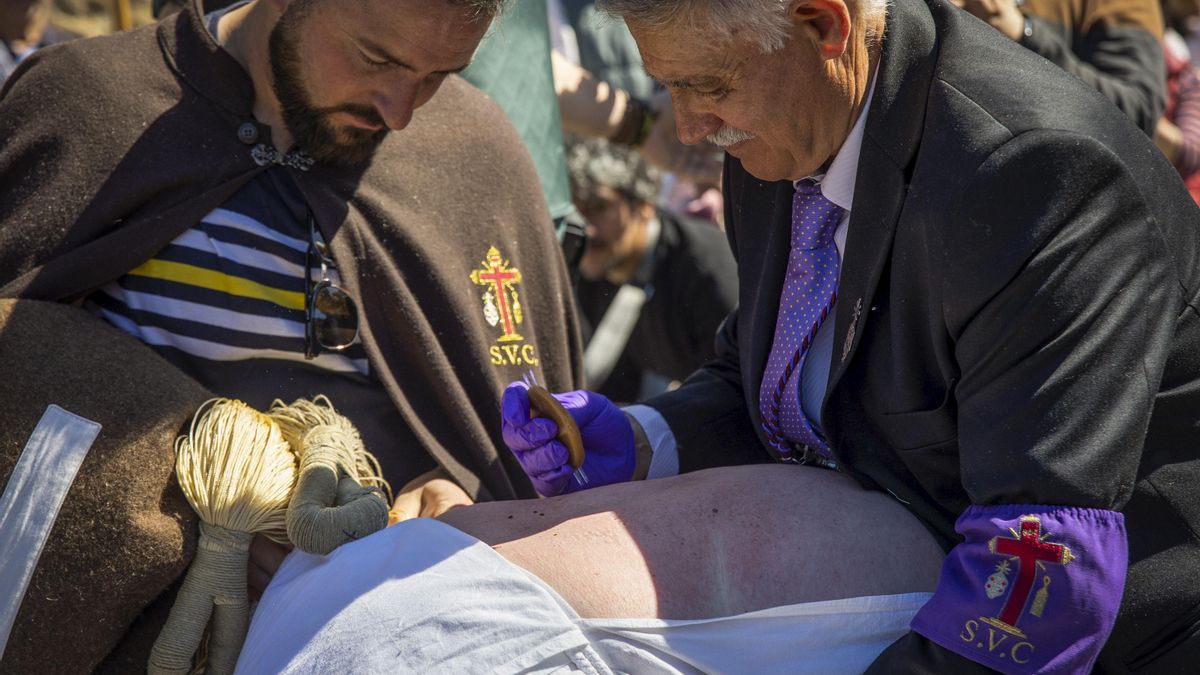 Un disciplinante es pinchado durante el Vía Crucis del municipio riojano de San Vicente de la Sonsierra, que acoge a los "picaos", quienes, con el rosto cubierto, flagelan su espalda, donde se autogolpean entre 800 y 1.000 veces con una madeja para, después, ser pinchados 12 veces con una "esponja" de cera virgen repujada de cristales y curar sus heridas con agua de romero. EFE/ Raquel Manzanares