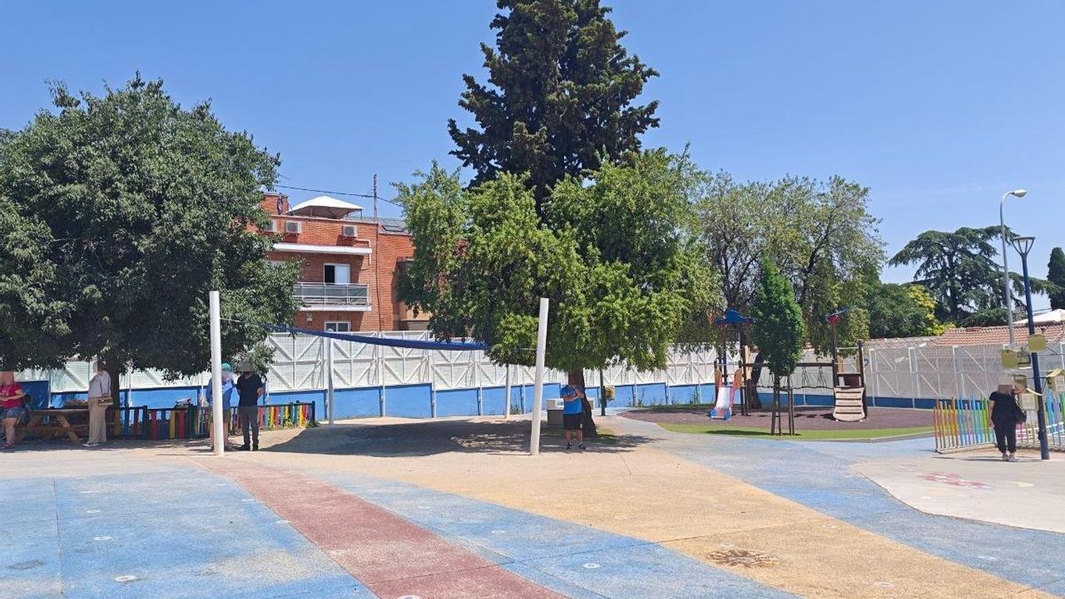 Las familias buscan la sombra mientras esperan a que los niños salgan del colegio.