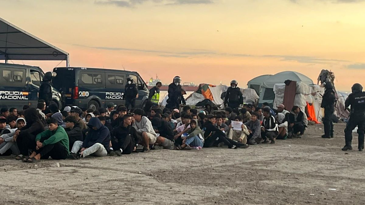 Un grupo de personas migrantes durante su desalojo del Guano en Ceuta, este domingo a primera hora de la mañana.
