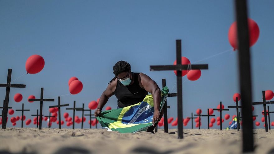 Una activista instala una bandera de Brasil en una representación escénica de la ONG Río de Paz por las víctimas del COVID-19