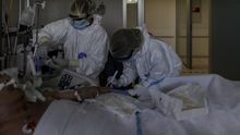 Personal sanitario totalmente protegido atiende a un paciente ingresado en la Unidad de Cuidados Intensivos del Hospital Infanta Sofía en San Sebastián de los Reyes (Madrid)