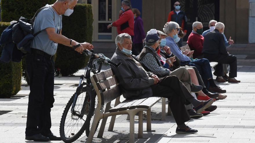 Varias personas descansan en un banco protegidos con mascarilla durante la segunda jornada en la capital leonesa por el confinamiento perimetral provocado por la Covid-19. EFE/ J. Casares