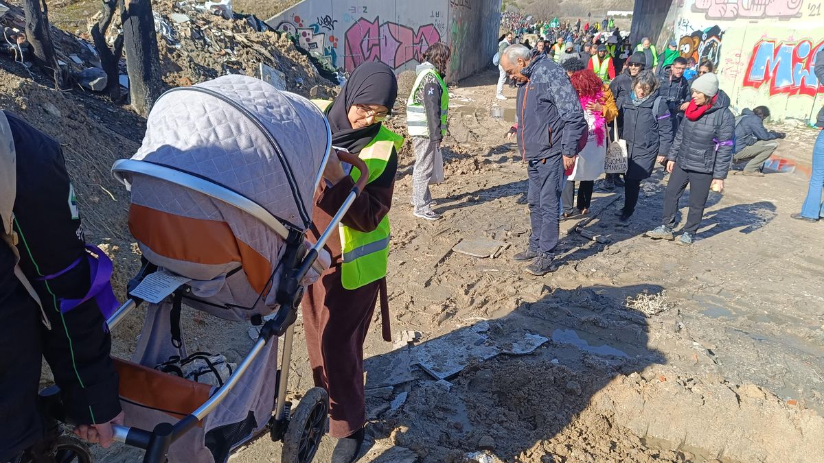 Una mujer sube con ayuda de un hombre un carrito de bebé por una cuesta embarrada de la Cañada Real este sábado.
