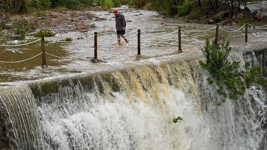 Un hombre cruza un badén inundable durante este lunes en Valencia