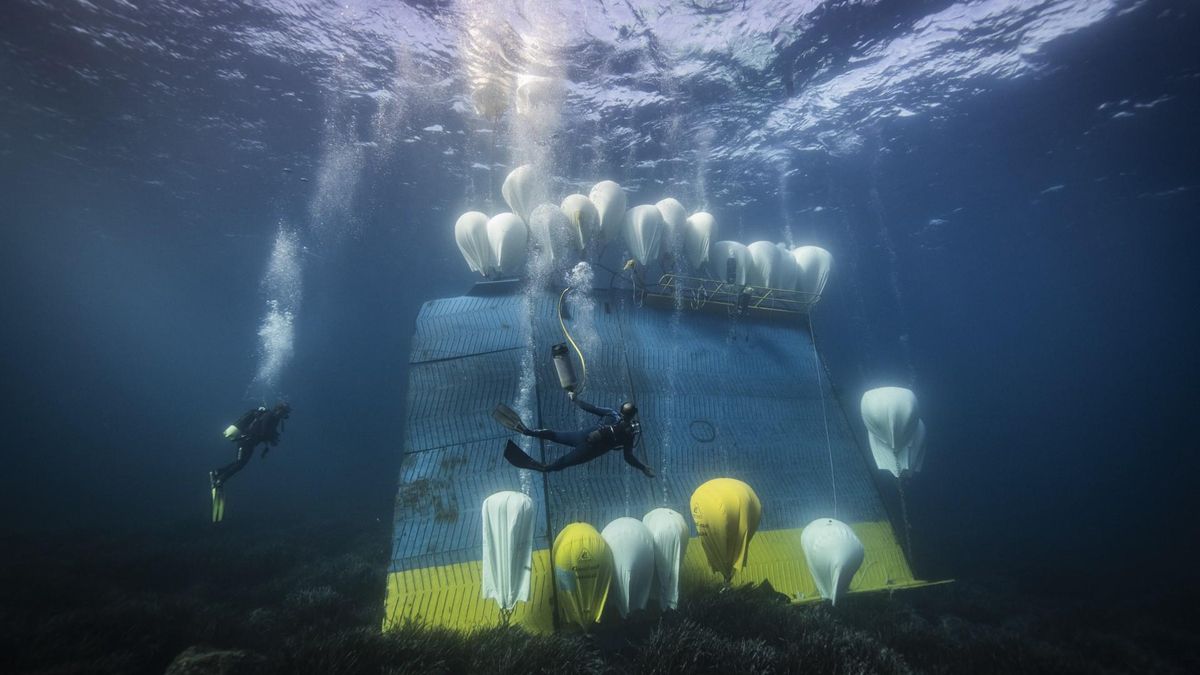 Dos buzos recogen la escotilla que ha perdido un buque de pasajeros sobre una pradera de posidonia mientras navegaba por la isla italiana de Linosa.