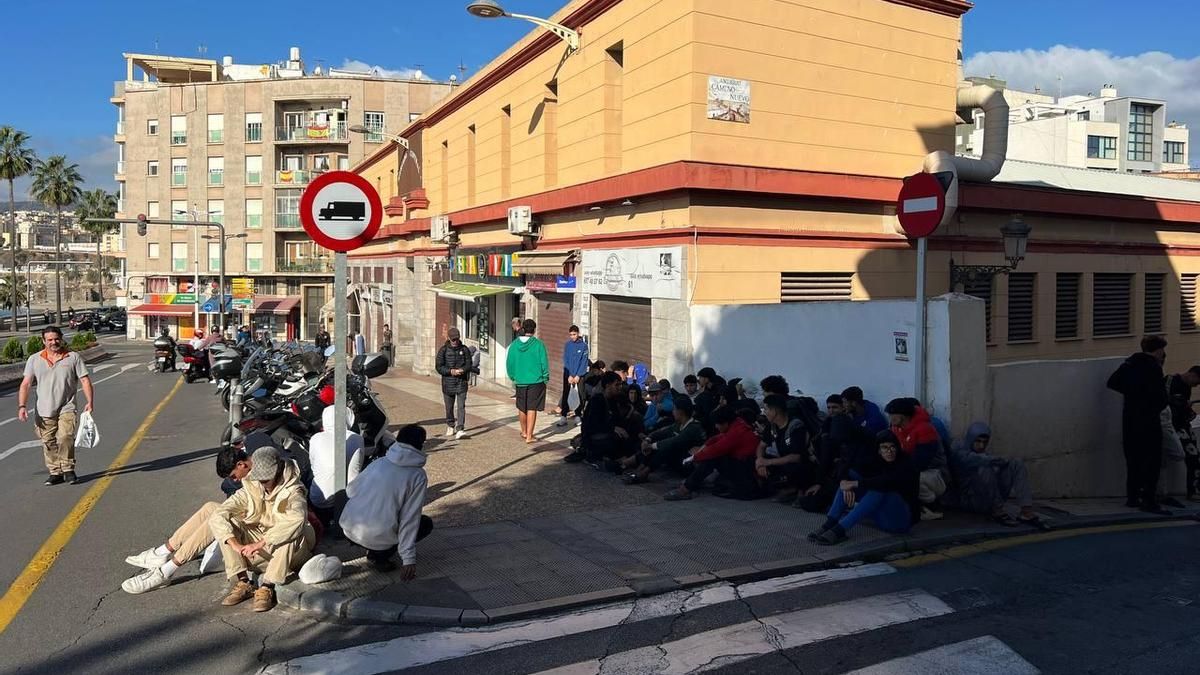 Un grupo de menores esperan en la calle frente a la Jefatura Policial en Ceuta, donde los filian.