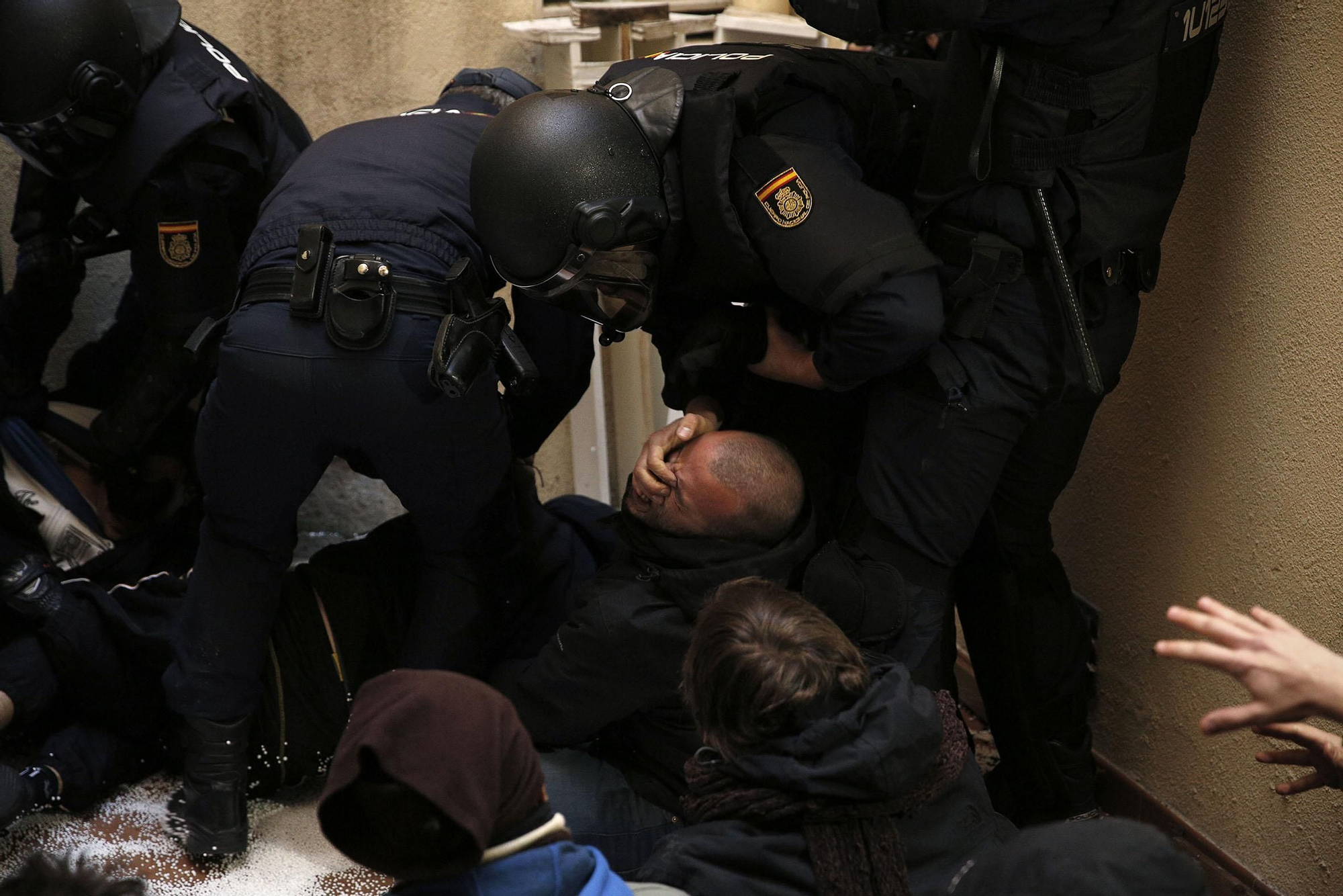 Un policía antidisturbio mete los dedos en los ojos de un activista al levantarle violentamente del suelo.