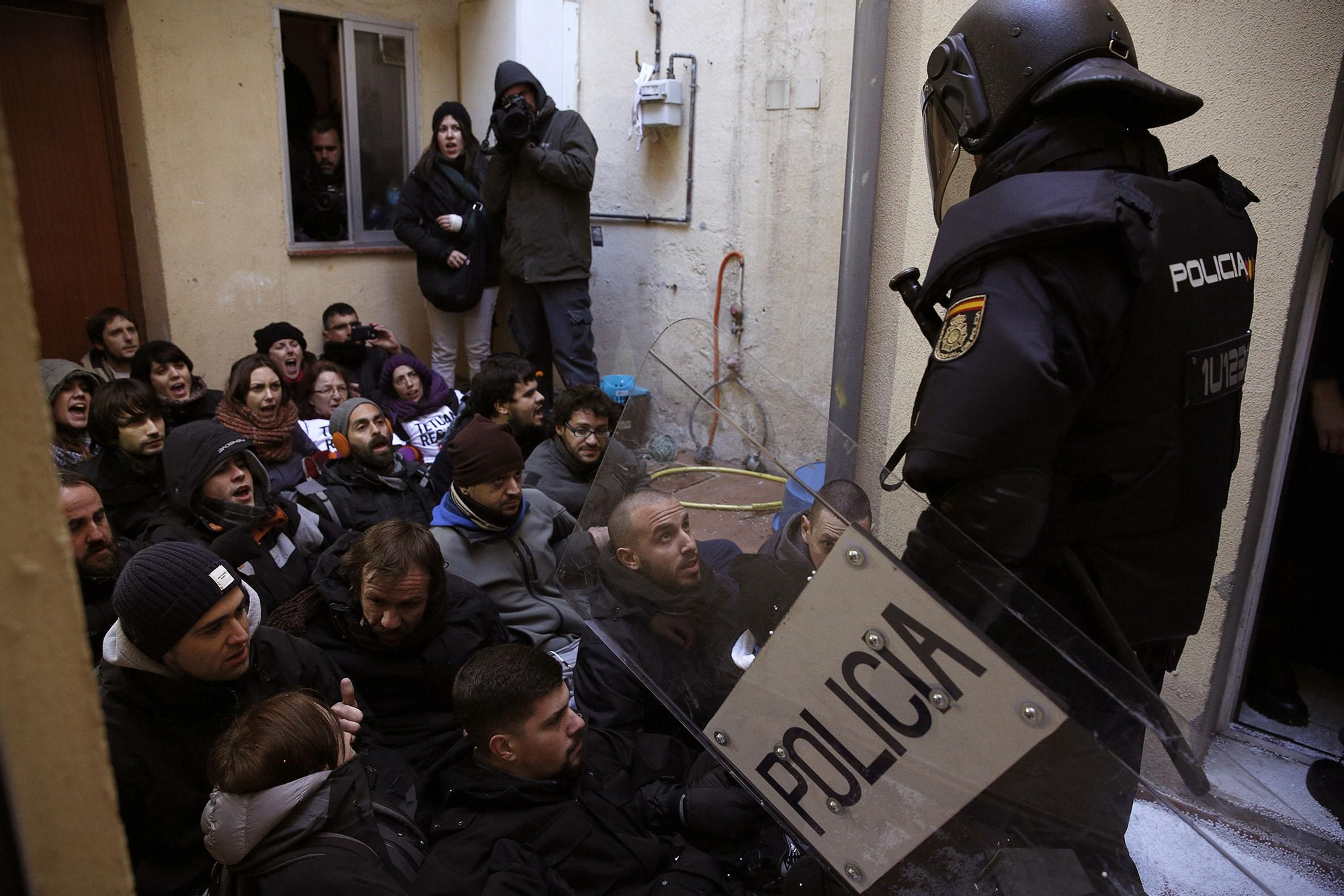 Un policía antidisturbios se dispone a sacar a los activistas que, sentados en el suelo, bloquean la puerta de entrada a la vivienda