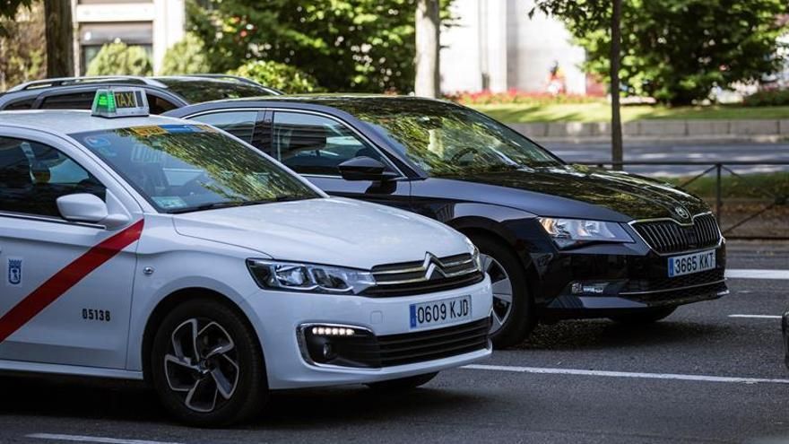 Un taxi y un vehículo VTC en las calles de Madrid.