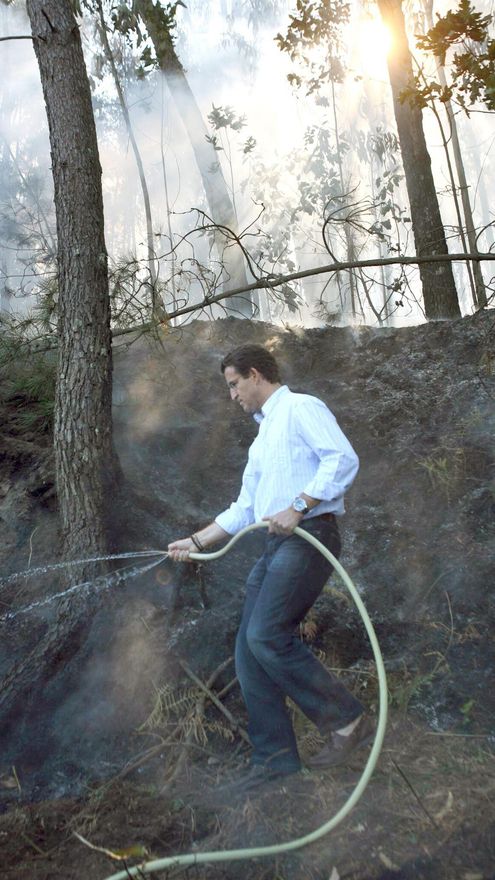 Alberto Núñez Feijóo sujeta una manguera en un incendio en Meis (Pontevedra) en agosto de 2006, cuando todavía estaba en la oposición y negaba las tramas incendiarias.