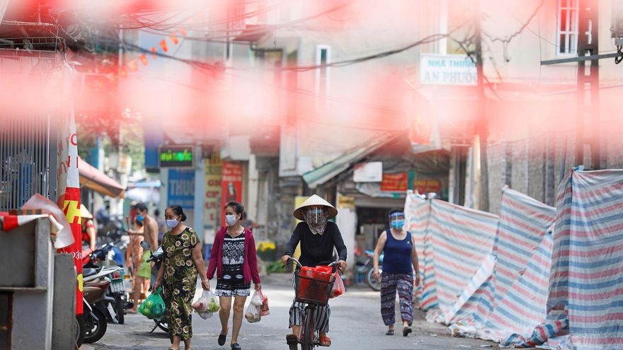 Una mujer circula en bicicleta en un área en cuarentena en Hanoi, Vietnam.
