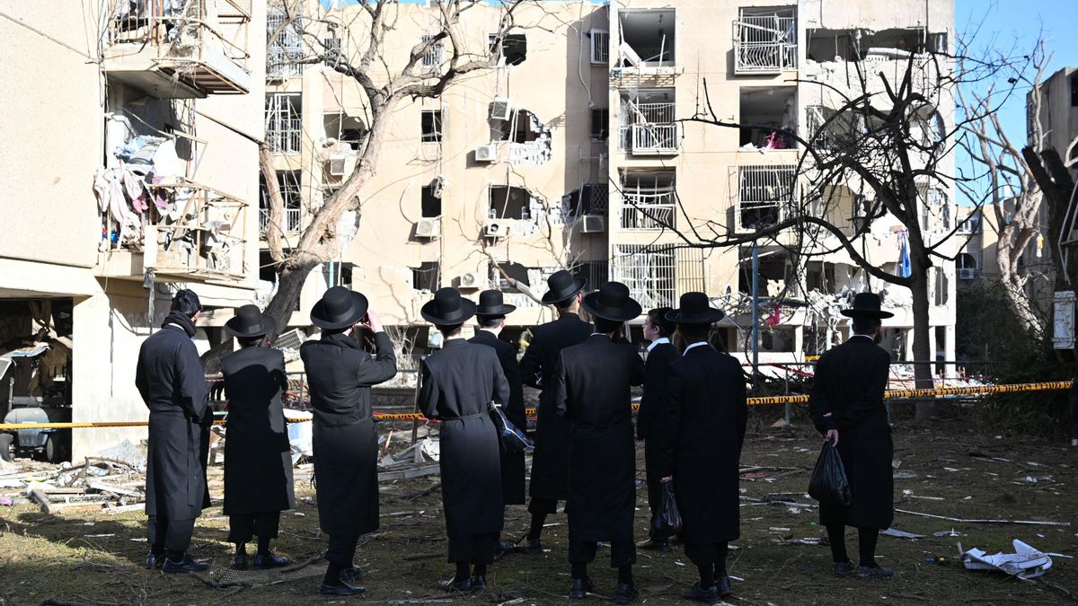 Un grupo de personas observa el daño en un bloque de edificios en Arad (Israel).