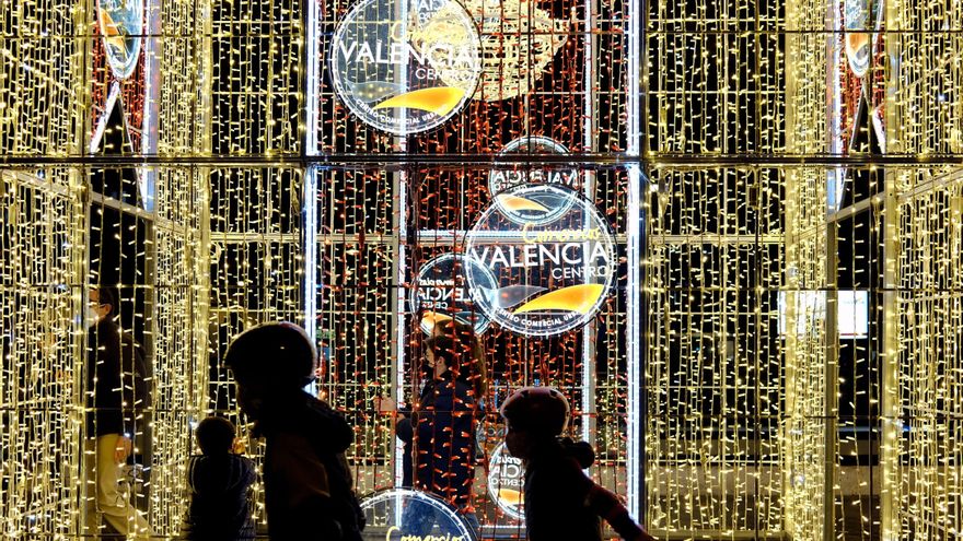 Unos niños juegan ante un cartel iluminado en el centro de Valencia. EFE/ Juan Carlos Cárdenas